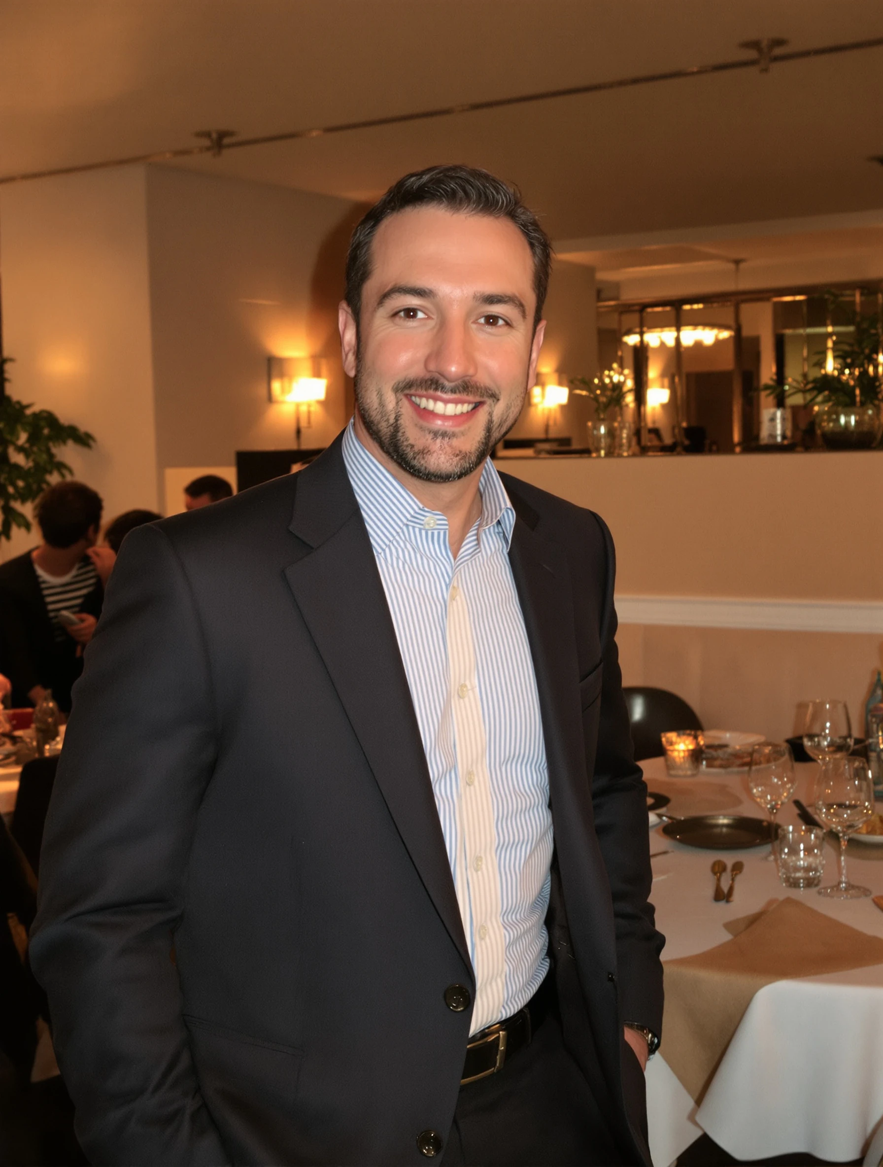 Well-dressed man in a tailored blazer without tie, standing in an upscale restaurant. Smart casual dinner date attire, w