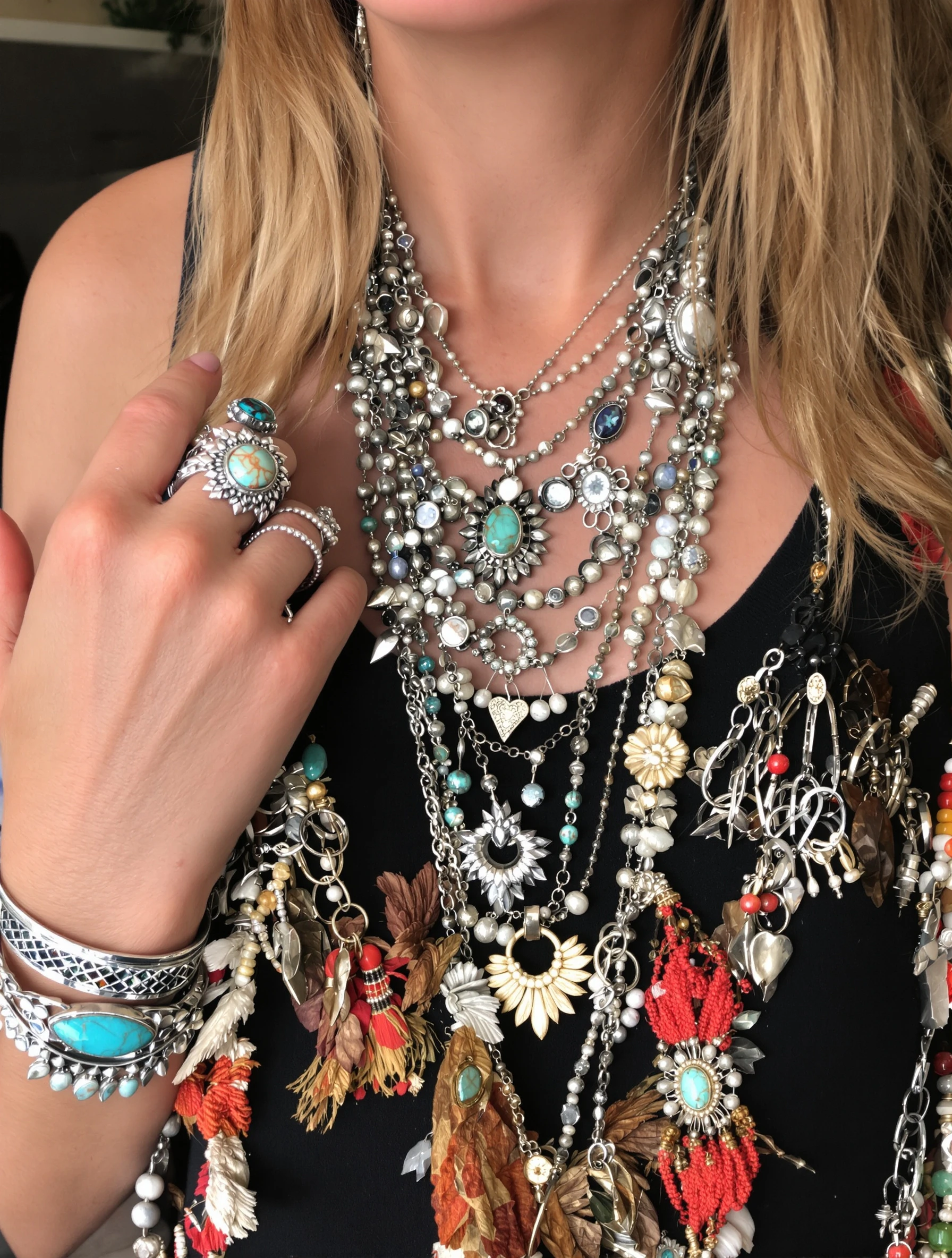 Woman with layered boho jewelry - necklaces, rings, bracelets stacked. Bohemian accessories, silver and turquoise, collected treasures, personal adornment.
