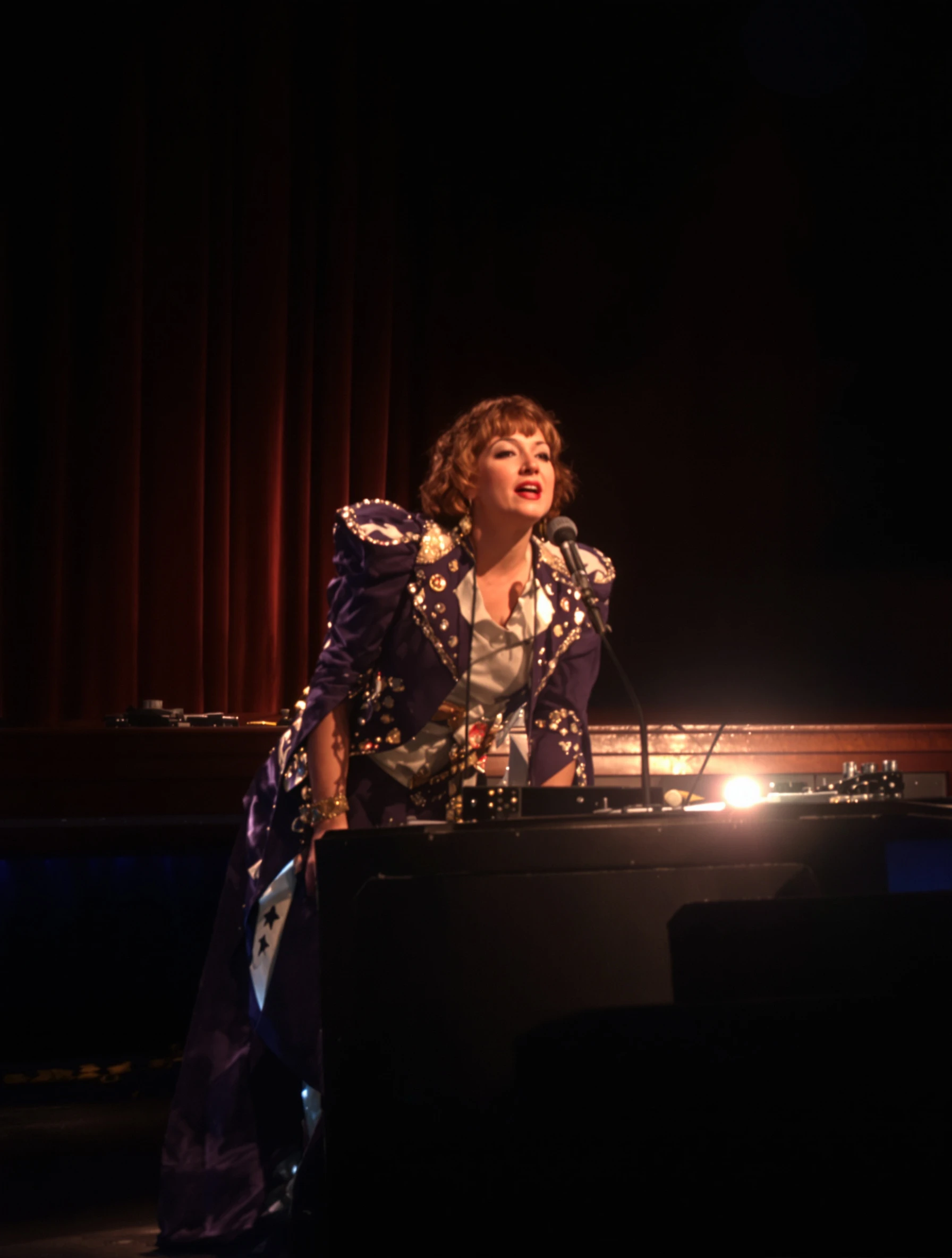 Woman performing on theater stage, dramatic lighting, emotional scene. Stage costume, theatrical expression, live performance, dramatic arts.