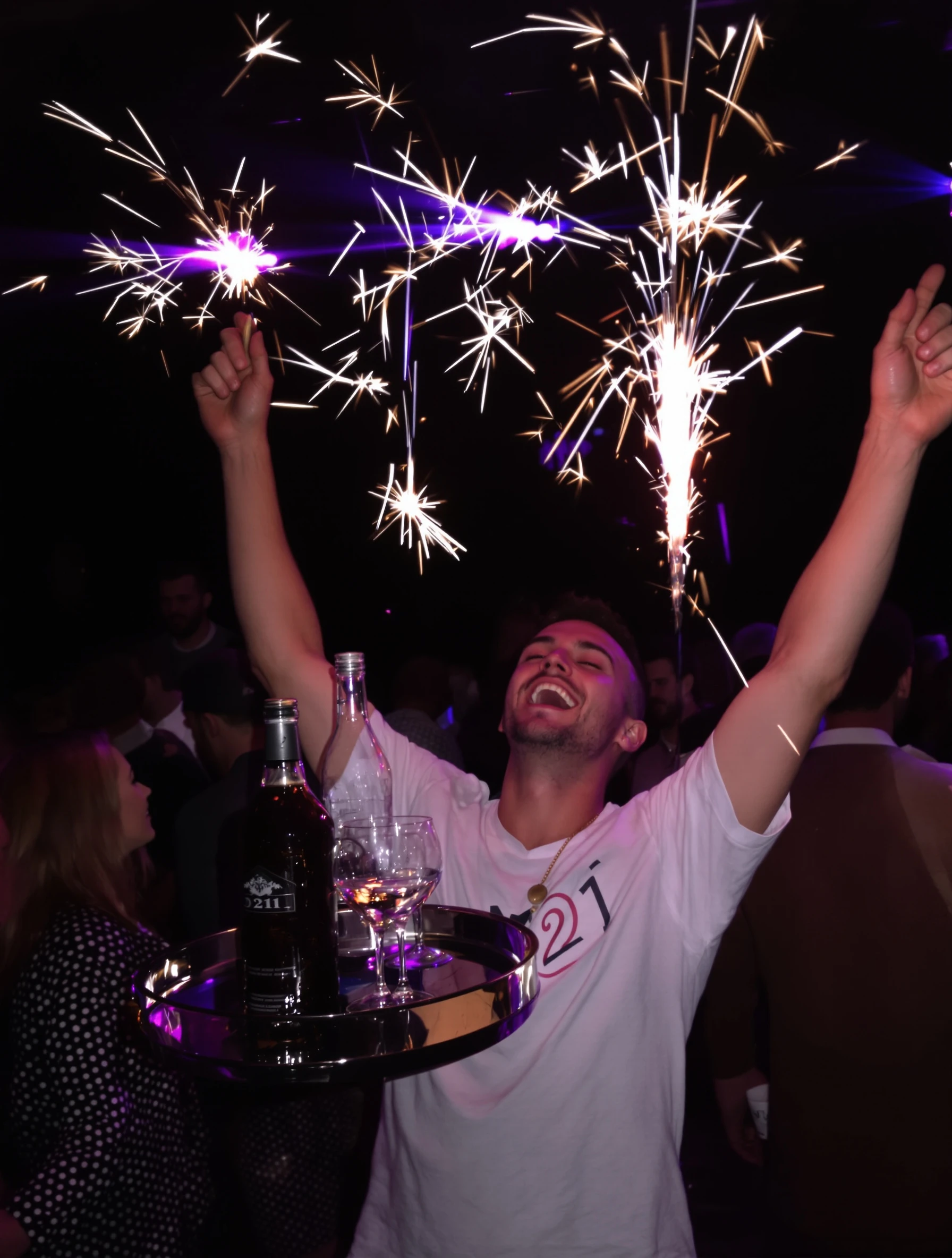 Man turning 21 in a club with a sparkler-topped bottle service tray held up beside him, purple and blue lights, arms raised, ecstatic expression.