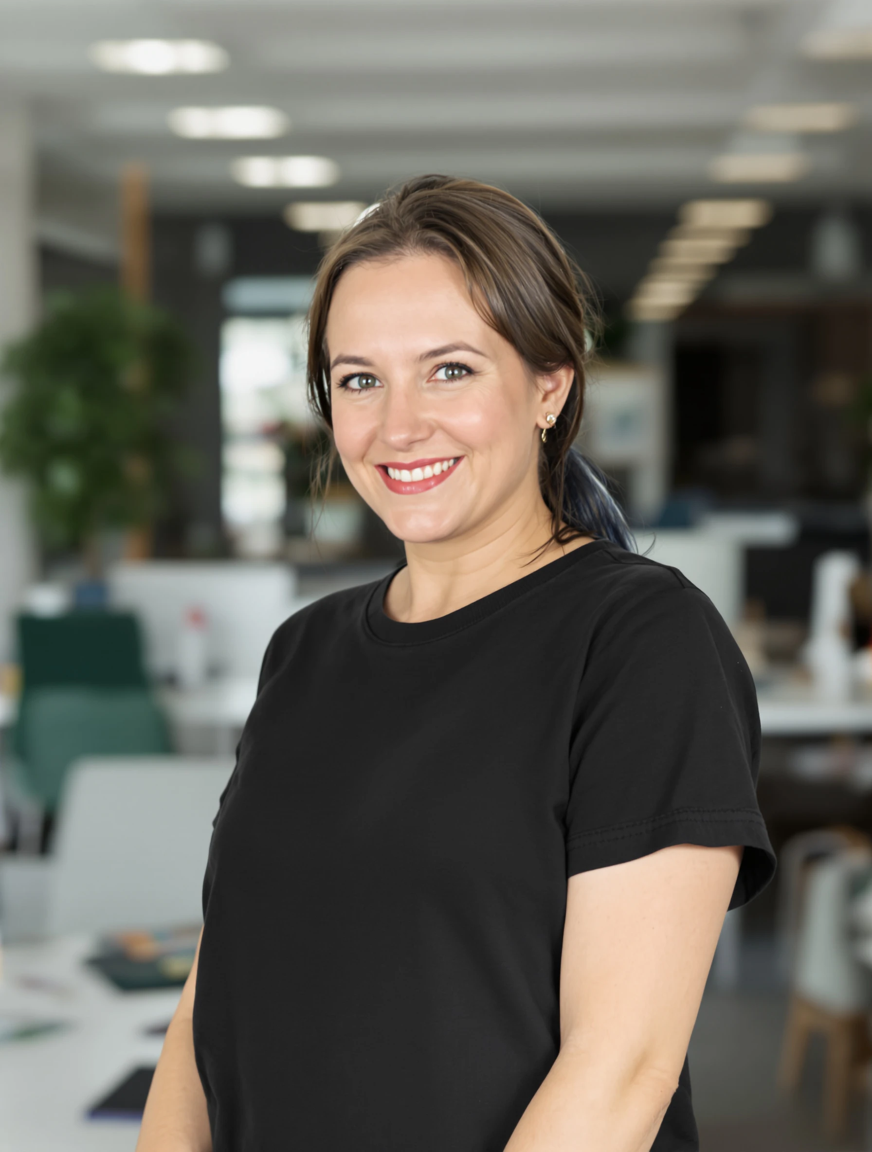 Tech headshot of a woman in a plain black crewneck t-shirt, minimal styling, bright modern office blurred behind her, relaxed smile.