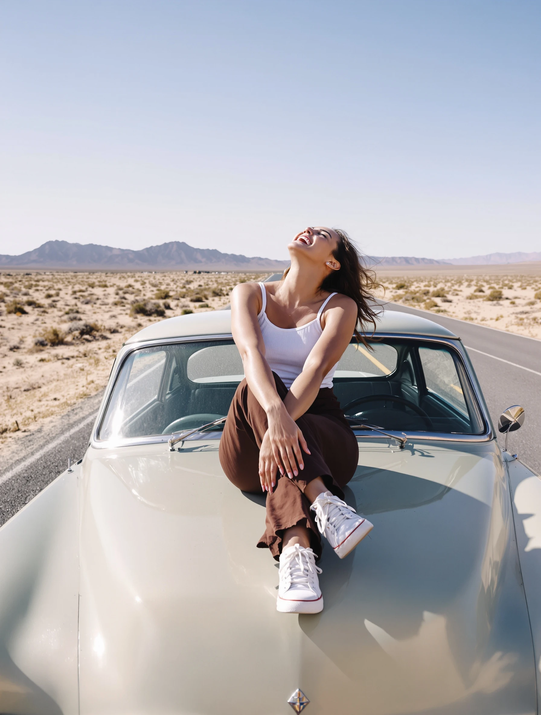 Woman sitting on the hood of a vintage car with her legs crossed at the ankles, leaning back on her hands, relaxed laugh, desert road.